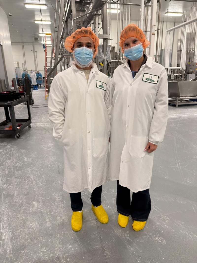 The Tribu founders in hairnets and lab coats on a cheese plant floor
